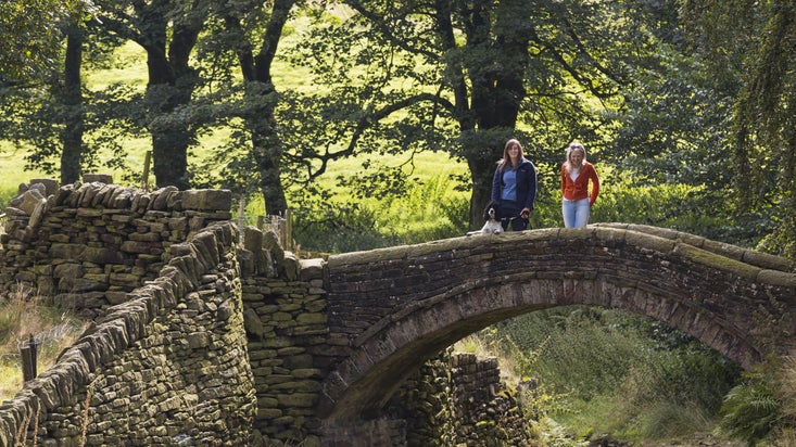 Visitors with their dog standing on Easter Gate Bridge, Marsden, Yorkshire.